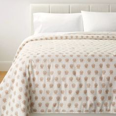 a bed with white and brown bedspread in a bedroom next to a window