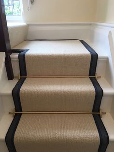 a set of stairs with black and white carpeting on the bottom, next to a window