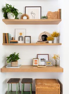 three wooden shelves with plants, pictures and other items on them in a white room