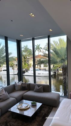 a living room filled with lots of furniture and large windows next to a body of water