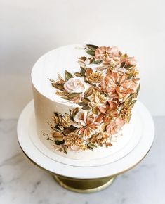 a white cake with flowers on it sitting on top of a table next to a marble counter