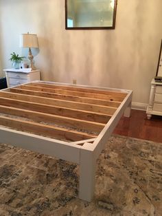 a bed frame made out of wood in a room with a rug on the floor