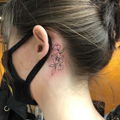 a woman's behind the ear tattoo with flowers on her left side ribcage