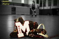 a pair of shoes sitting on top of a basketball court with the letter m next to it