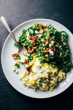 a white plate topped with food and a spoon next to it on a black table