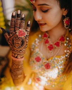 a woman with henna on her hand and flowers in her hair is looking at the camera