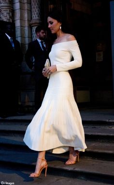 a woman in a white dress is walking down the steps with her hand on her hip