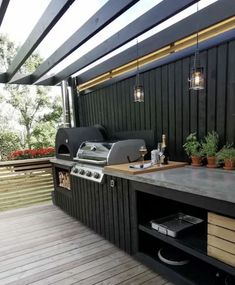 an outdoor kitchen with grill, sink and potted plants on the counter top area