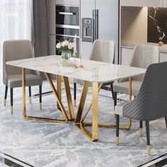 a marble dining table with gold legs and grey upholstered chairs in a modern kitchen