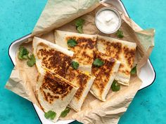 several quesadillas are on a plate with sour cream