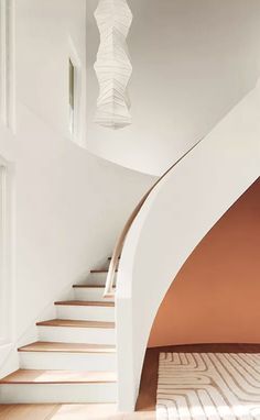 a spiral staircase in a home with white walls and wood floors, along with an area rug on the floor