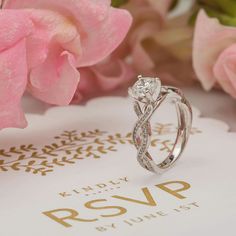 a diamond ring sitting on top of a card next to pink flowers