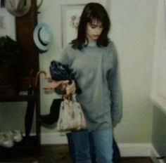 a young man holding a purse in his hand while standing next to a cat on the floor