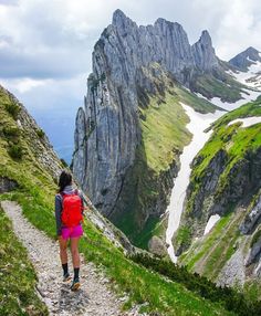 a person with a backpack is walking up a trail to the top of a mountain