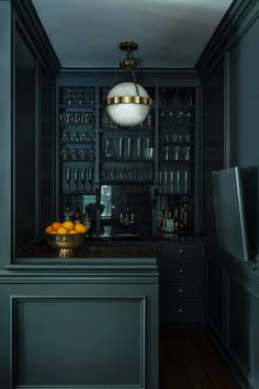 a kitchen with black cabinets and glassware on the counter top in front of a television