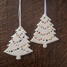 two ceramic christmas trees hanging from strings