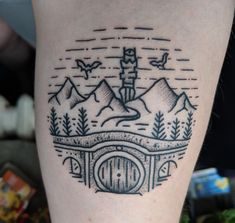 a tattoo on the leg of a person with mountains in the background and a gate