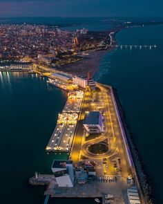 an aerial view of a city at night with lights on the water and buildings in the background