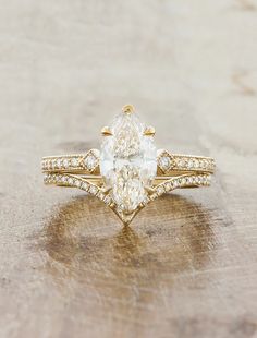 a pear shaped diamond engagement ring set on top of a wooden table