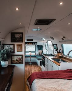 the interior of an rv with wood flooring and white walls, windows, and cabinets