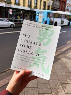 a person holding up a book on the street