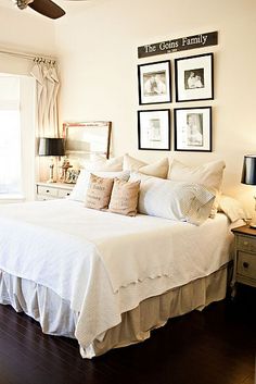 a white bed sitting in a bedroom next to a window with pictures on the wall