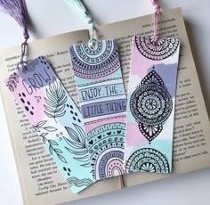 two bookmarks with the words enjoy the little things printed on them and tassels