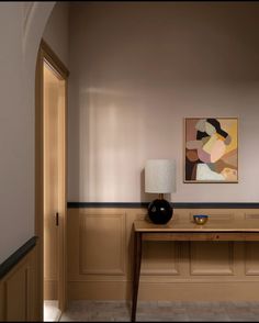 a painting on the wall above a table in a room with wood paneling and beige walls