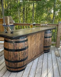 an outdoor bar made out of wooden barrels on a deck with wine glasses sitting on it