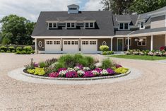 a driveway with flowers in the middle and two garages on each side, along with a gravel path leading up to it