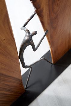 a metal figurine standing on one foot in front of a wooden door