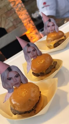 two plates topped with hamburgers covered in fake hair and buns on top of them