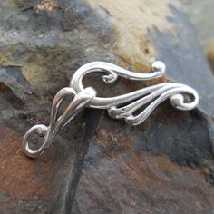 a silver brooch sitting on top of a rock