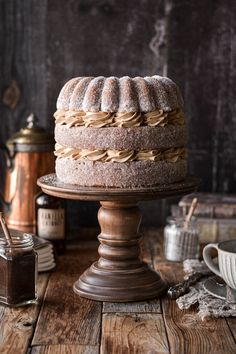 a cake sitting on top of a wooden table next to a cup and saucer