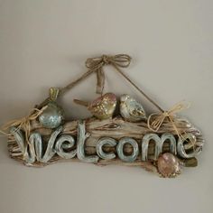 a welcome sign made out of driftwood with birds on it and the word welcome