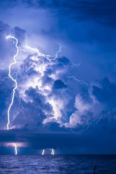 a large cloud filled with lightning over the ocean