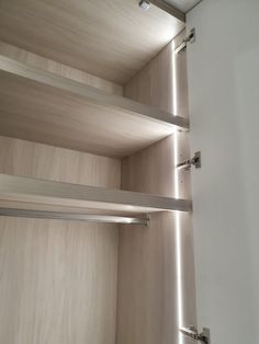 an empty closet with some shelves and lights on the wall above it in front of a door