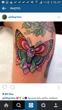 a colorful butterfly tattoo on the leg with flowers and leaves around it's wings