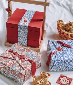 several wrapped gifts sitting on top of a white sheet covered bed next to gold decorations