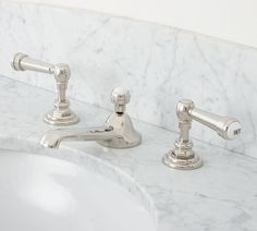 two chrome faucets sitting on top of a marble counter