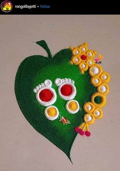 a green heart with yellow and red flowers on it's side, sitting on top of a table