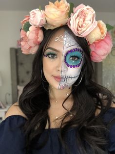 a woman with makeup and flowers in her hair wearing a skull face paint make - up