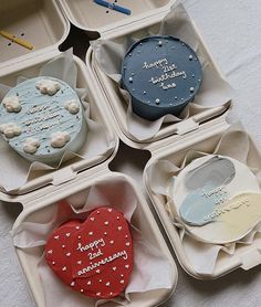 four heart shaped cupcakes in small boxes with writing on them