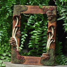 a wooden frame decorated with mushrooms and ferns