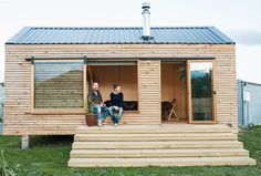 two people sitting on the steps of a tiny house