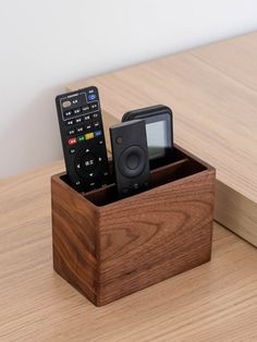 two remote controls in a wooden box on a table