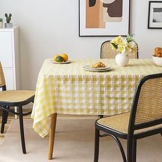 a dining room table with yellow and white checkered cloth on it, surrounded by black chairs