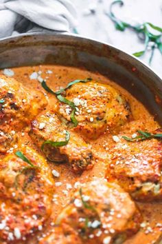 a pan filled with meat covered in sauce and garnished with parmesan cheese