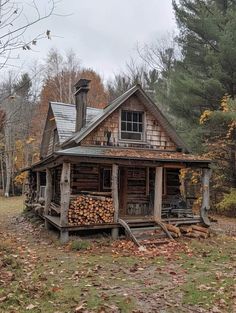 an old log cabin in the woods with lots of wood stacked on the front porch