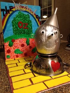 a metal teapot with a heart on it sitting next to a card that says the wizard of oz